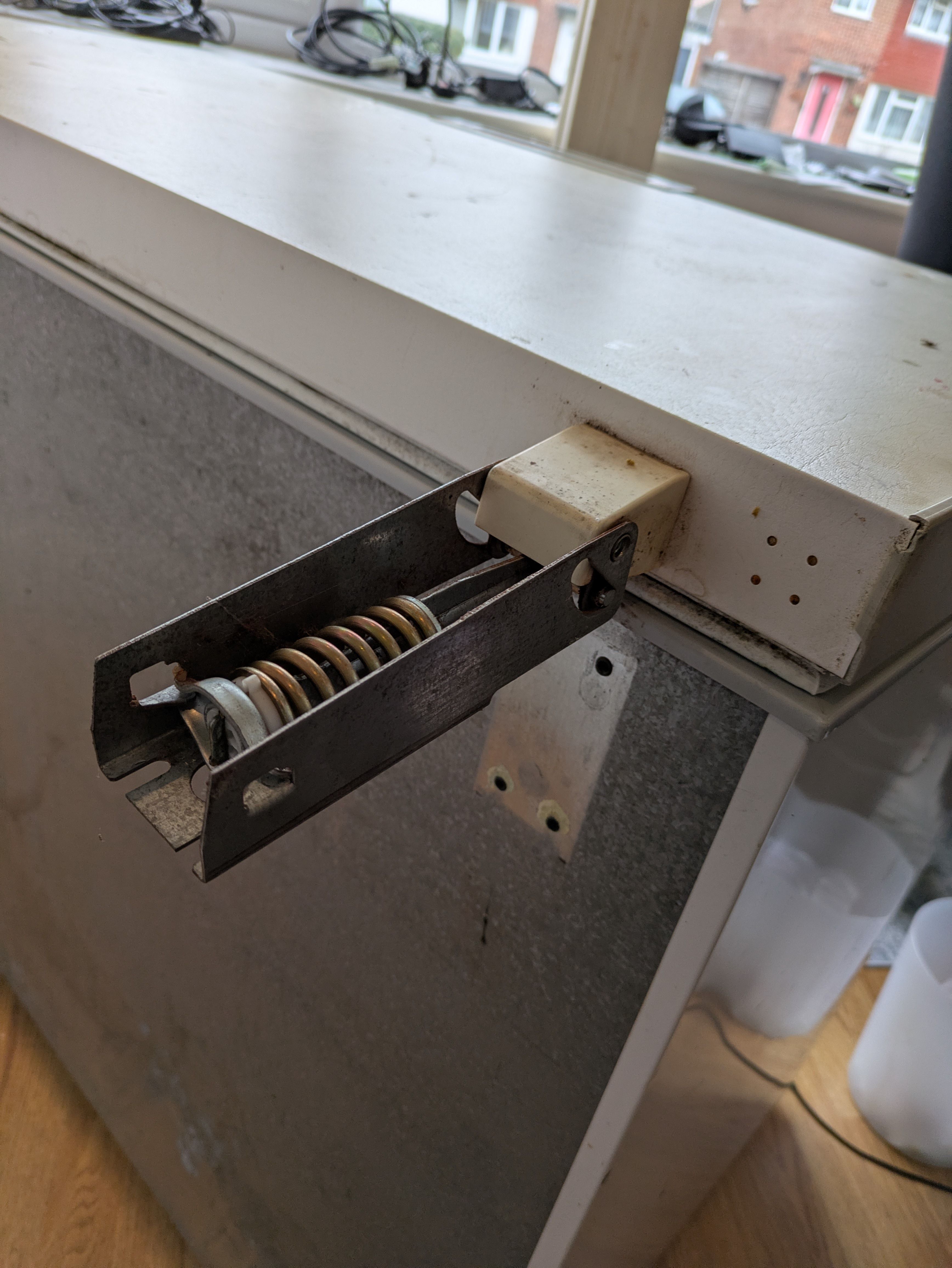 Unscrewing the hinge from the body of the freezer